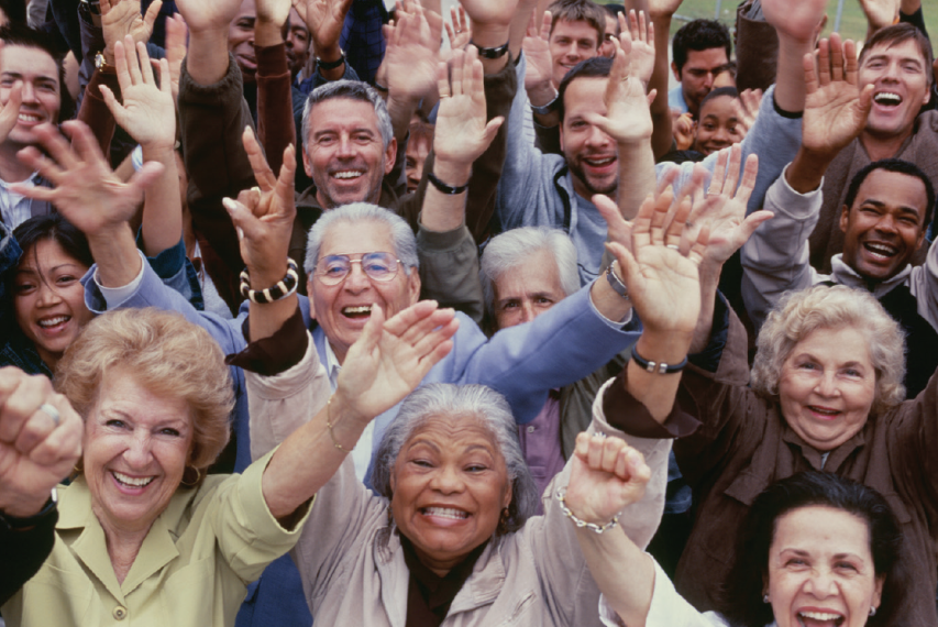 Crowd of older adults raising hands and smiling