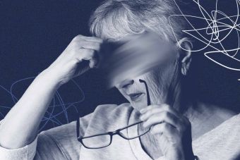 Elderly woman with glasses rubbing head