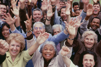 Crowd of older adults raising hands and smiling